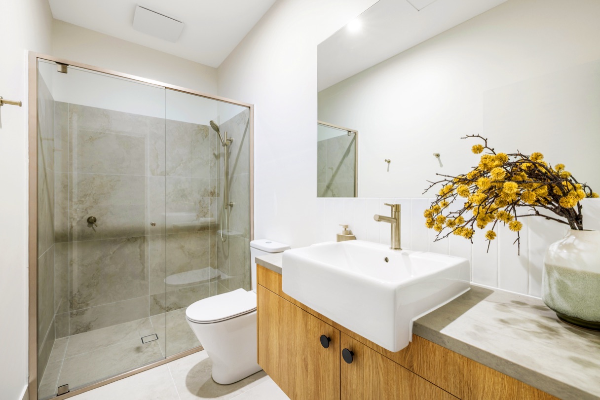 Bathroom with a walk-in shower, timber vanity and stone-look benchtop.